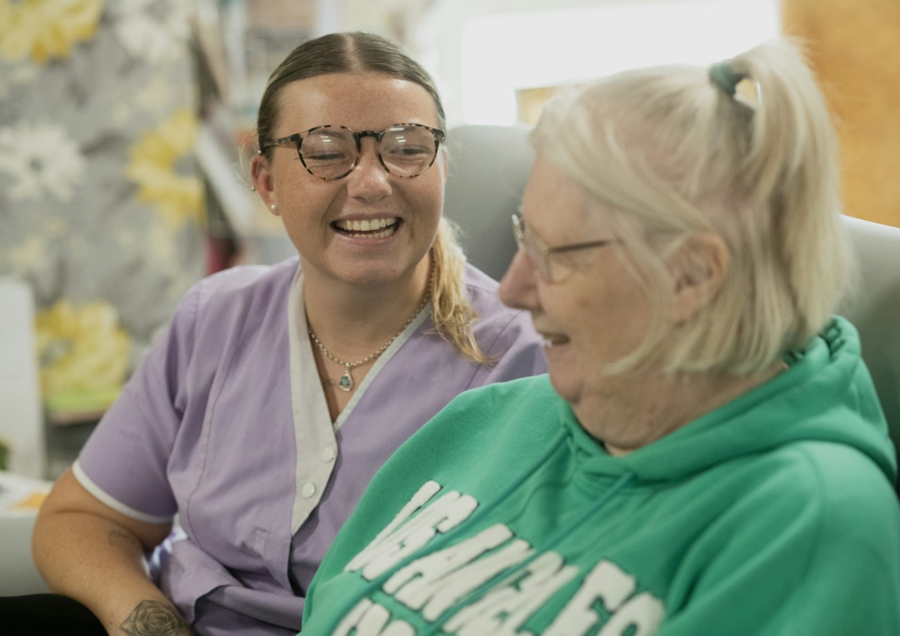 Clinical staff member laughing with a senior patient