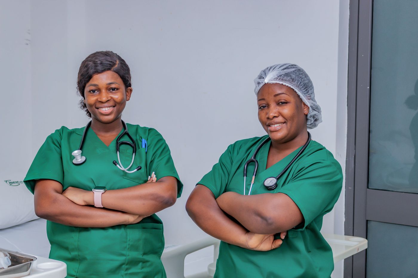 Two nurses in green scrubs smiling